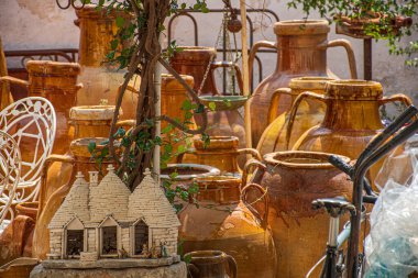 Tipik Puglia seramik sürahileri veya kavanozları ve birkaç Trulli hatırası, Alberobello, Puglia, İtalya 'da konik çatısı olan geleneksel Apulian taş duvar kulübeleri.