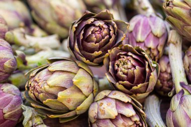 Sokak gıda pazarında yeşil yapraklı taze yeşil enginarlar. Yaklaş.