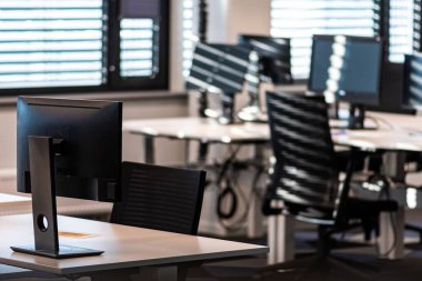 Ofis kapalı ve boş çünkü Covid veya Coronavirus salgını, bilgisayar, sandalye ve masalar kapalı bir pencerenin gölgesinde ve yatay levhalar ile perdeler. Ev kavramından çalışmak