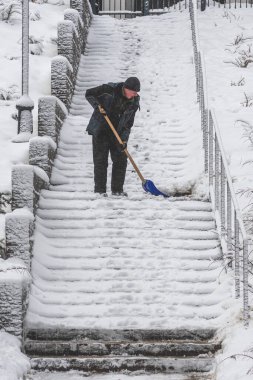 Vilnius, Litvanya - 31 Ocak 2022: Büyük bir kar fırtınasının ardından merdivenlerde kar küreyen adam