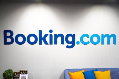 Vilnius, Litvanya - 13 Şubat 2022: Booking.com logosu bir tiyatro sahnesi, seyahat ve otel konsept endüstrisindeki gibi yapay ışıklarla aydınlatılan bir ofisin beyaz duvarında