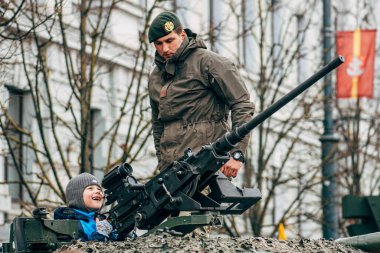 Vilnius, Litvanya - 16 Şubat 2022: Çocuk ya da çocuk gülerek bir tank ya da askeri aracın tepesinde oynuyordu.