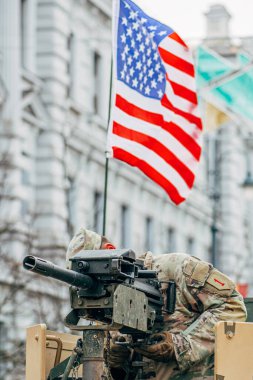 Vilnius, Litvanya - 16 Şubat 2022: Amerikan bayrağı taşıyan bir makineli tüfeğin tepesinde ABD Deniz Piyade Birliği askeri, eğitime ya da savaşa hazırdır.