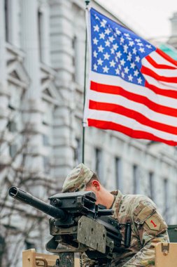 Vilnius, Litvanya - 16 Şubat 2022: Amerikan bayrağı taşıyan bir makineli tüfeğin tepesinde ABD Deniz Piyade Birliği askeri, eğitime ya da savaşa hazırdır.