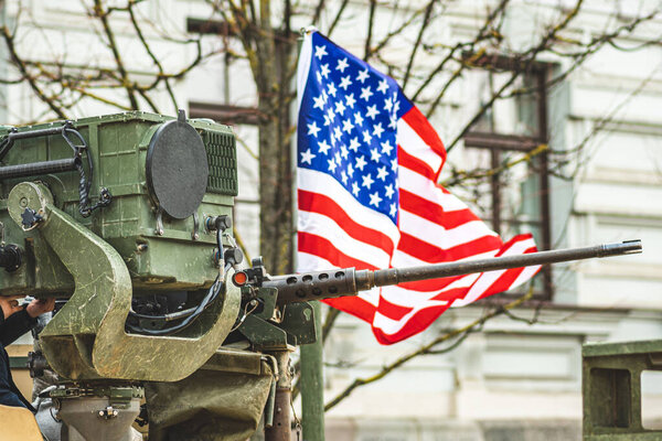 Machine gun mounted on United States Marine Corps forces tank or military vehicle, USA or US army, with American flag waiving on background