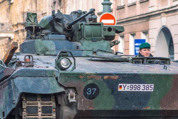 Vilnius, Lithuania - February 16 2022: Armored crawler tank with cannon and female soldier driving in the city. German Army, member of NATO or North Atlantic Treaty Organization, NATO response force
