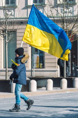 Vilnius Litvanya - 11 Mart 2022: Kışlık giysileri olan çocuk veya çocuk, Ukrayna bayrağı ve şapkası. Putin ve Rusya 'nın neden olduğu Ukrayna' daki savaşı dikey protesto