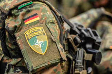 Berlin, Almanya - 29 Mart 2022: Almanya bayrağı ve NATO savaş grubunun bir asker üniforması üzerindeki sembolü