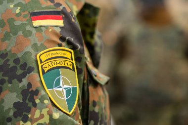 Berlin, Almanya - 29 Mart 2022: Almanya bayrağı ve NATO savaş grubunun bir asker üniforması üzerindeki sembolü