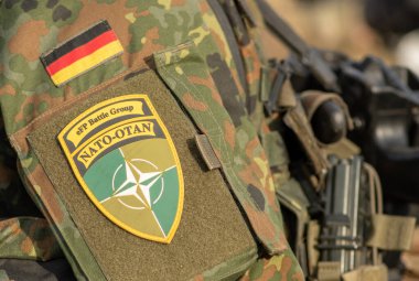 Berlin, Almanya - 29 Mart 2022: Almanya bayrağı ve NATO savaş grubunun bir asker üniforması üzerindeki sembolü