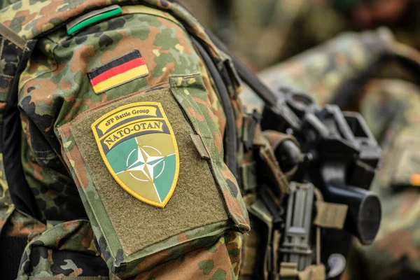 Berlin, Almanya - 29 Mart 2022: Almanya bayrağı ve NATO savaş grubunun bir asker üniforması üzerindeki sembolü