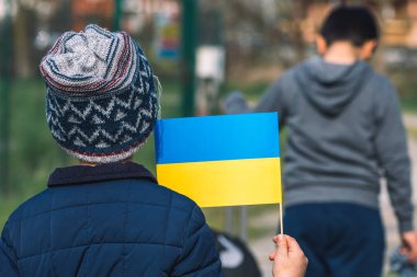 Ukrayna 'daki savaş sırasında Putin ve Rusya' nın, mültecilerin, mültecilerin kampının neden olduğu kışlık giysileri, şapkası ve Ukrayna bayrağı taşıyan çocuklar veya çocuklar.