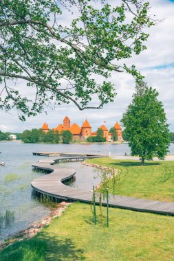Trakai, Vilnius, Litvanya - 3 Haziran 2022: Ortaçağ Trakai şatosu, Vilnius, Litvanya, Doğu Avrupa, yazın güzel göller ve doğa ile çevrili tahta köprü, tekne ve turistler, dikey