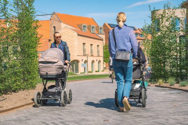 Odense, Danimarka - 23 Mayıs 2022: Danimarka 'nın Odense kentindeki modern binalar arasında yeni bir bisiklet yolu ya da yolda yürüyen bebek arabalı güzel sarışın kızlar