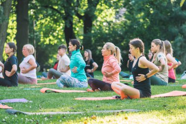 Vilnius, Litvanya - 22 Haziran 2022: Güzel kızlar yaz aylarında halka açık bir parkta çimlerin üzerinde yoga ya da spor yapıyorlar
