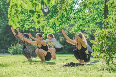 Vilnius, Litvanya - 22 Haziran 2022: Güzel kızlar yaz aylarında halka açık bir parkta çimlerin üzerinde yoga ya da spor yapıyorlar
