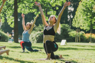 Vilnius, Litvanya - 22 Haziran 2022: Güzel kızlar yaz aylarında halka açık bir parkta çimlerin üzerinde yoga ya da spor yapıyorlar
