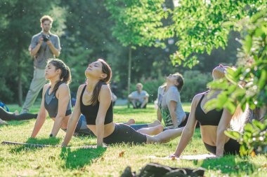 Vilnius, Litvanya - 22 Haziran 2022: Güzel kızlar yaz aylarında halka açık bir parkta çimlerin üzerinde yoga ya da spor yapıyorlar