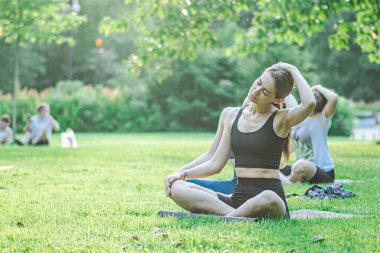 Vilnius, Litvanya - 22 Haziran 2022: Güzel kızlar yaz aylarında halka açık bir parkta çimlerin üzerinde yoga ya da spor yapıyorlar