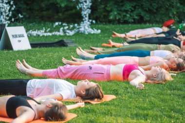 Vilnius, Litvanya - 22 Haziran 2022: Güzel kızlar yaz aylarında halka açık bir parkta çimlerin üzerinde yoga ya da spor yapıyorlar