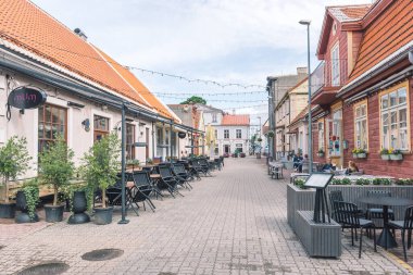 Parnu, Estonya, Avrupa - 19 Haziran 2022: Geleneksel evleri ve restoranların masalarında oturan insanlar ile Parnu eski kasaba caddesi