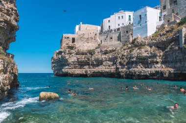 Polignano a Mare, Puglia, İtalya - 30 Ağustos 2021: Beyaz taş evler, uçurum, sahil, mavi deniz ve Akdeniz doğasıyla çevrili güzel Polignano a Mare manzarası