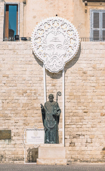 Bari, Puglia, Italy - July 20 2021: San Nicola, Saint Nicholas bronze statue with traditional Apulian illuminations, Bari old town, Puglia, Italy, vertical