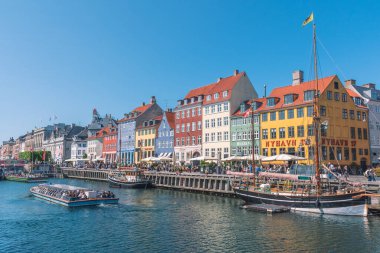 Kopenhag, Danimarka - 23 Mayıs 2022: Geleneksel evler ve eski ahşap gemiler, Nyhavn Kanalı veya New Harbour, Kanal ve eğlence bölgesi boyunca seyahat eden teknelerin renkli cepheleriyle güzel manzara