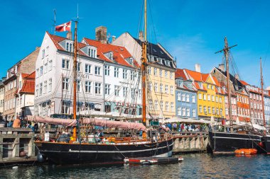 Kopenhag, Danimarka - 23 Mayıs 2022: Geleneksel evler ve eski ahşap gemiler, Nyhavn Kanalı veya New Harbour, Kanal ve eğlence bölgesi boyunca seyahat eden teknelerin renkli cepheleriyle güzel manzara