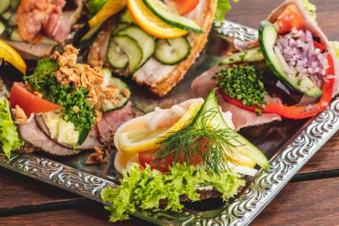Geleneksel Danimarka usulü Smrrebrd veya açık sandviçler bir tabakta servis edilir, remoulade ile biftek, domates ve doğranmış yaban turpu Danimarka çavdar ekmeği, yumurta, karides, limon ve mayonez ile servis edilir.