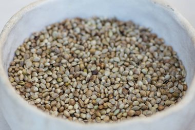 Dried hemp cannabis seeds in a white ceramic bowl, close up