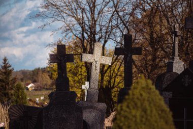Litvanya 'daki antik bir mezarlıkta, güneş ışığıyla aydınlatılan haçlardan biriyle eski bir taş haçları kesiyor.