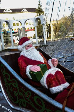 Sekiz ren geyiği tarafından çekilen kızakla uçan Noel Baba, beyaz sakallı, kırmızı elbiseli ve hediyelerle dolu bir kızağı var.