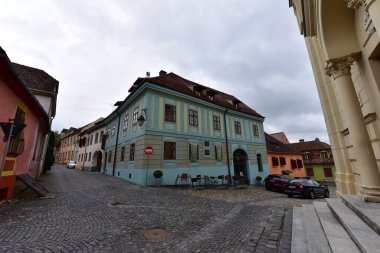 Sighisoara Kalesi 'ndeki ortaçağ binaları laik evler, tarihi anıtlar, her birinin adı, tarihi ve plaketleri Rumen İngilizcesi ve Almancası sokak ve binaları.