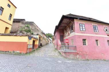 Sighisoara Kalesi 'ndeki ortaçağ binaları laik evler, tarihi anıtlar, her birinin adı, tarihi ve plaketleri Rumen İngilizcesi ve Almancası sokak ve binaları.