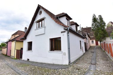 Sighisoara Kalesi 'ndeki ortaçağ binaları laik evler, tarihi anıtlar, her birinin adı, tarihi ve plaketleri Rumen İngilizcesi ve Almancası sokak ve binaları.