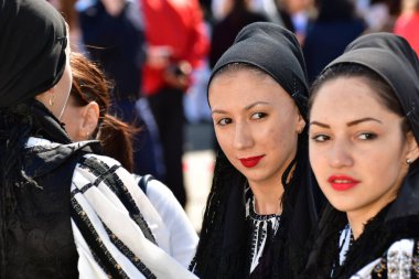 Geleneksel siyah motiflerle dikilmiş ulusal keten pastoral kostümlü Romen halk dansçıları, geleneksel siyah şapka giyen erkekler ve püsküllü siyah fular giyen kadınlar