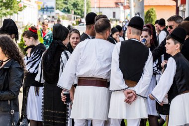 Geleneksel siyah motiflerle dikilmiş ulusal keten pastoral kostümlü Romen halk dansçıları, geleneksel siyah şapka giyen erkekler ve püsküllü siyah fular giyen kadınlar