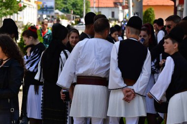 Geleneksel siyah motiflerle dikilmiş ulusal keten pastoral kostümlü Romen halk dansçıları, geleneksel siyah şapka giyen erkekler ve püsküllü siyah fular giyen kadınlar