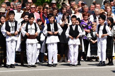 Geleneksel siyah motiflerle dikilmiş ulusal keten pastoral kostümlü Romen halk dansçıları, geleneksel siyah şapka giyen erkekler ve püsküllü siyah fular giyen kadınlar