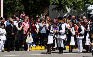 Geleneksel siyah motiflerle dikilmiş ulusal keten pastoral kostümlü Romen halk dansçıları, geleneksel siyah şapka giyen erkekler ve püsküllü siyah fular giyen kadınlar