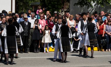 Geleneksel siyah motiflerle dikilmiş ulusal keten pastoral kostümlü Romen halk dansçıları, geleneksel siyah şapka giyen erkekler ve püsküllü siyah fular giyen kadınlar