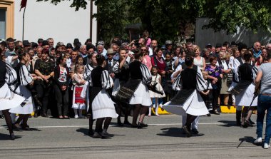 Geleneksel siyah motiflerle dikilmiş ulusal keten pastoral kostümlü Romen halk dansçıları, geleneksel siyah şapka giyen erkekler ve püsküllü siyah fular giyen kadınlar