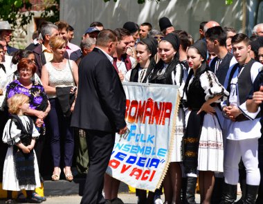 Geleneksel siyah motiflerle dikilmiş ulusal keten pastoral kostümlü Romen halk dansçıları, geleneksel siyah şapka giyen erkekler ve püsküllü siyah fular giyen kadınlar