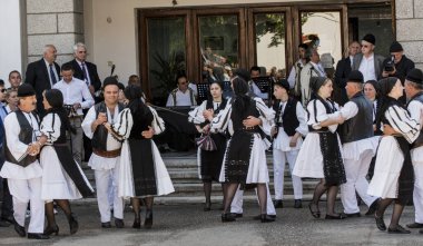 Geleneksel siyah motiflerle dikilmiş ulusal keten pastoral kostümlü Romen halk dansçıları, geleneksel siyah şapka giyen erkekler ve püsküllü siyah fular giyen kadınlar