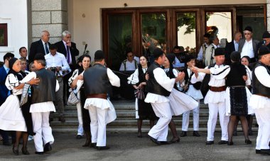 Geleneksel siyah motiflerle dikilmiş ulusal keten pastoral kostümlü Romen halk dansçıları, geleneksel siyah şapka giyen erkekler ve püsküllü siyah fular giyen kadınlar