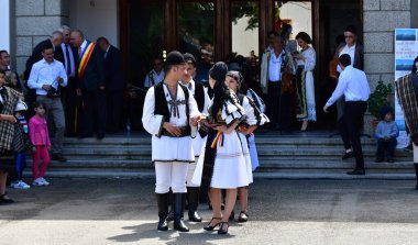 Geleneksel siyah motiflerle dikilmiş ulusal keten pastoral kostümlü Romen halk dansçıları, geleneksel siyah şapka giyen erkekler ve püsküllü siyah fular giyen kadınlar