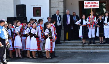 Transilvanya 'dan halk dansçıları tavus kuşu boncukları ve tüyleriyle süslenmiş astrakhan kuzu derisi şapkalar giyer, beyaz keten gömlek ve pantolon, geniş deri kemer, ulusal bayrağı temsil eden üç renkli köşegen.