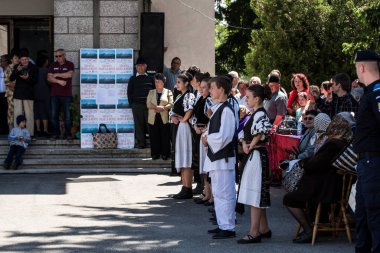 Geleneksel siyah motiflerle dikilmiş ulusal keten pastoral kostümlü Romen halk dansçıları, geleneksel siyah şapka giyen erkekler ve püsküllü siyah fular giyen kadınlar