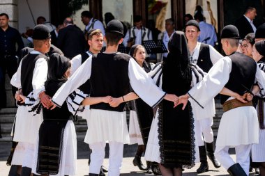 Geleneksel siyah motiflerle dikilmiş ulusal keten pastoral kostümlü Romen halk dansçıları, geleneksel siyah şapka giyen erkekler ve püsküllü siyah fular giyen kadınlar